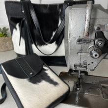 Load image into Gallery viewer, Studio shot of handmade cowhide bags next to industrial sewing machine. Made by Marge & Rudy