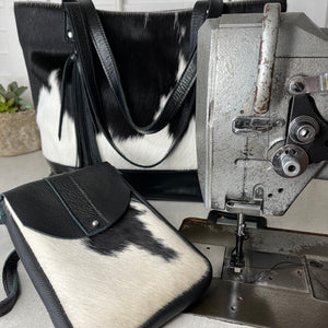 Studio shot of handmade cowhide bags next to industrial sewing machine. Made by Marge & Rudy