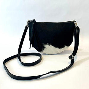Handcrafted leather cowhide crossbody bag with zippered closure in black and white spotted hair on hide