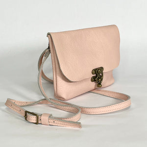 side view of handmade pink leather crossbody bag featuring antique brass clasp and buckle